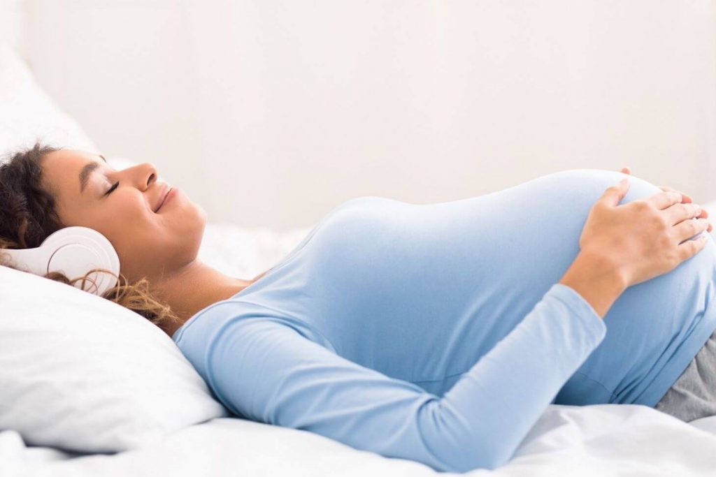 Donna incinta che si rilassa con la musica: tecnica di rilassamento per il parto
